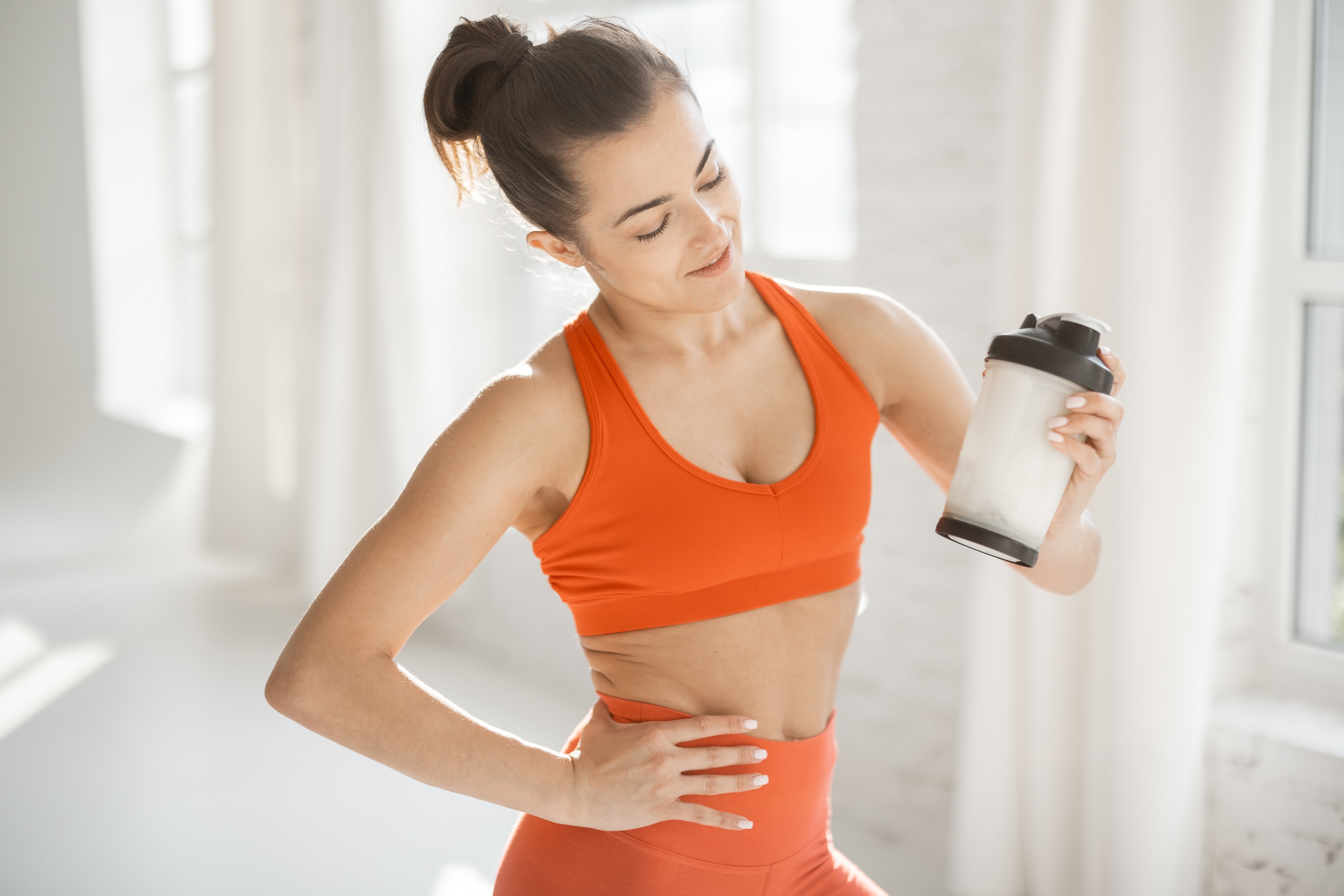 Young woman showing how to take collagen in a protein shaker bottle